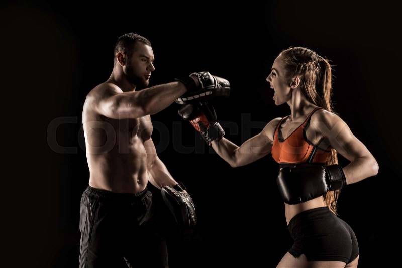 Sporty muscular young man and woman boxing together isolated on black , stock photo