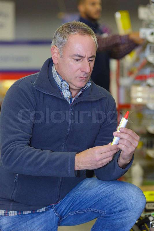 Smiling man customer picking sealing component in household shop, stock photo