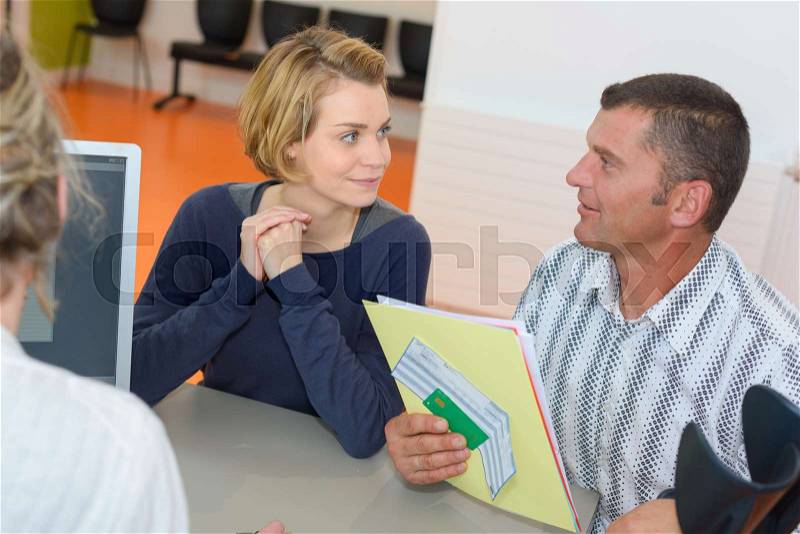 Couple talking with salesman and singing contract in the office, stock photo