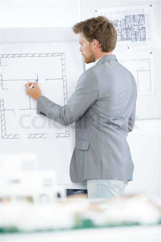 Architect drawing sketches of construction on a white board, stock photo