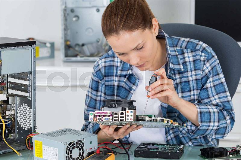 Female electronician repairing computer motherboard, stock photo
