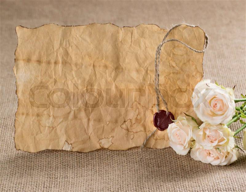 Ancient parchment with red wax seal and roses on sackcloth , stock photo