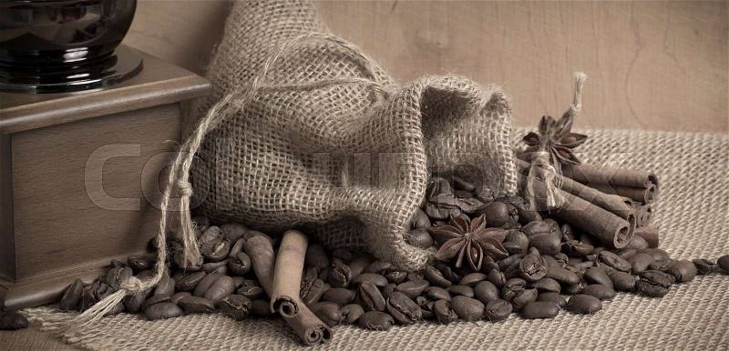 Coffee grains with cinnamon on sackcloth with bag and coffee mill. For this photo applied toning in retro style, stock photo