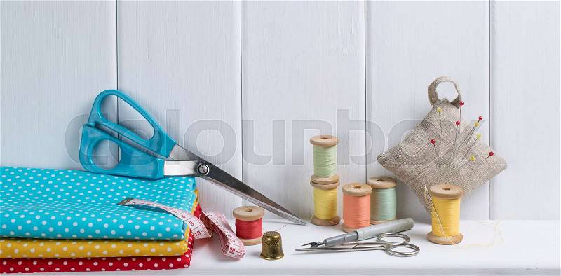 Interior design for seamstress. Set of reel of thread, centimeter, fabric, thimble and scissors, seam ripper, needle and pins for sewing and needlework on the wooden shelf , stock photo
