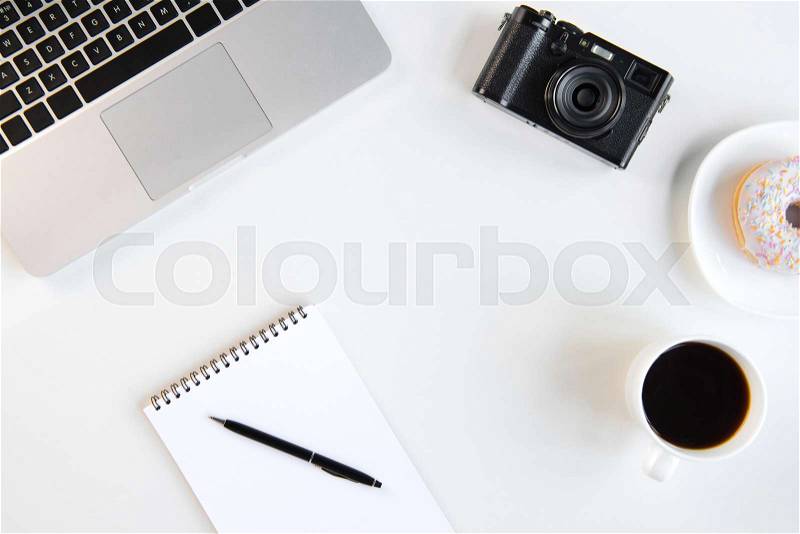 Top view of laptop, blank notebook with pen, cup of coffee and camera at workplace, stock photo
