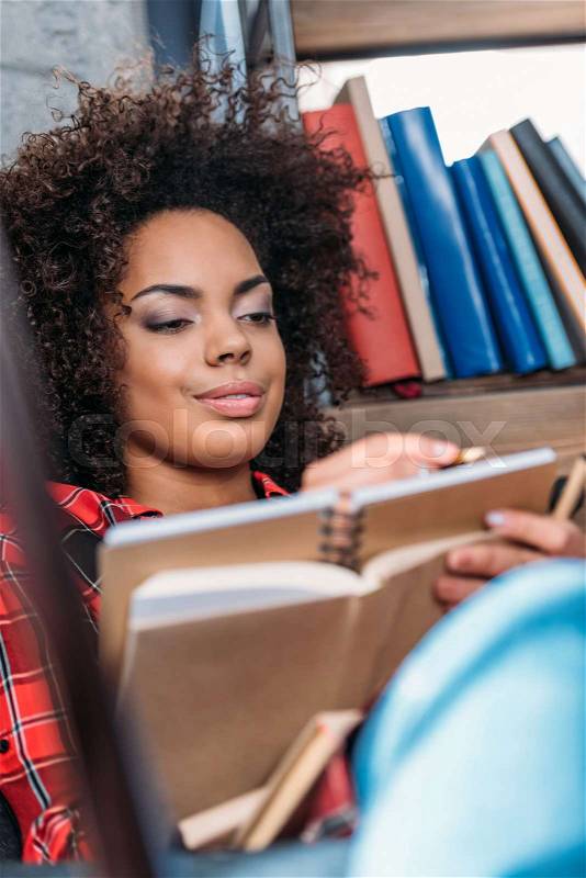 Attractive young african american student studying with books and textbooks , stock photo