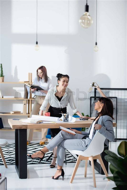 Young multiethnic businesswomen in formal wear working at office together, stock photo