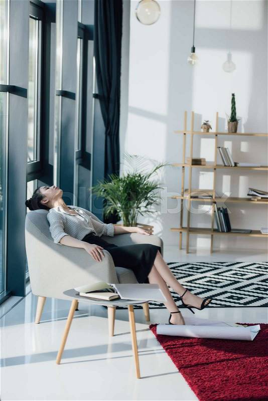 Young tired asian businesswoman sitting in chair with closed eyes, stock photo