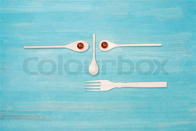Top view of wooden kitchen utensils with cherry tomatoes on blue table top, stock photo