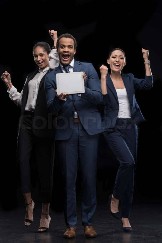 Group of business people holding digital tablet and celebrating success isolated on black, stock photo