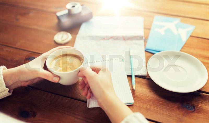 Vacation, tourism, travel, destination and people concept - close up of hands with coffee cup and travel stuff, stock photo
