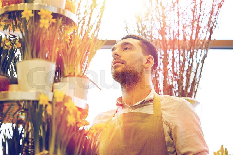 People, business, sale and floristry concept - florist man with narcissus flowers at flower shop, stock photo