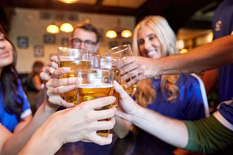 Sport, soccer, people and leisure concept - happy friends or football fans clinking beer glasses at bar or pub, stock photo