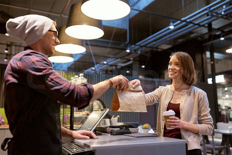 Small business, food, people and service concept - happy female customer with coffee cup taking paper bag from man or barman at vegan cafe, stock photo