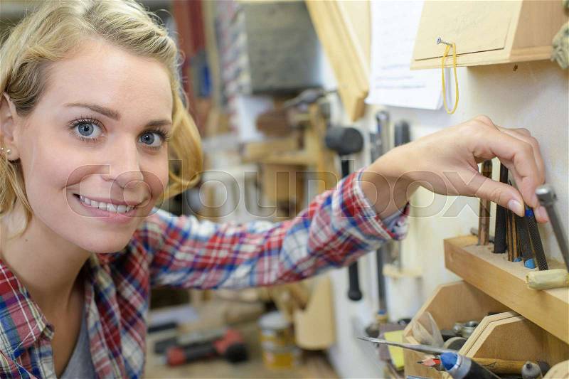 Pretty female carpenter at work in her workplace, stock photo
