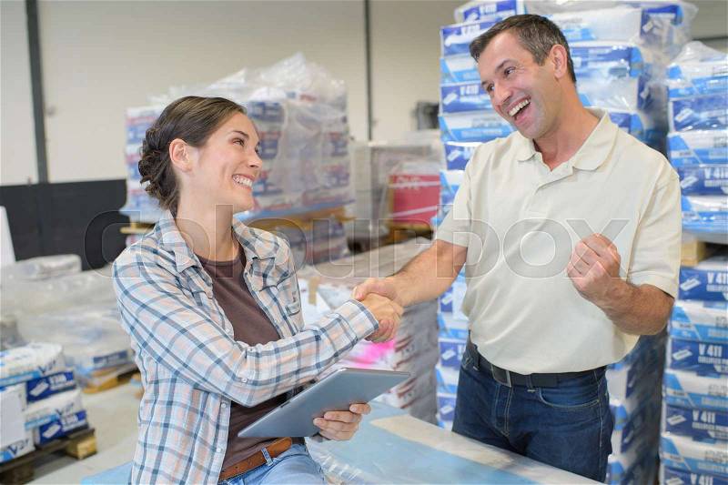 Female worker shake hand with male worker in warehouse, stock photo