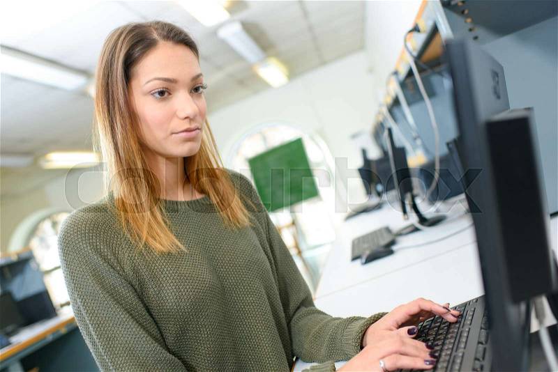 Pretty female student looking at a desktop computer screen, stock photo