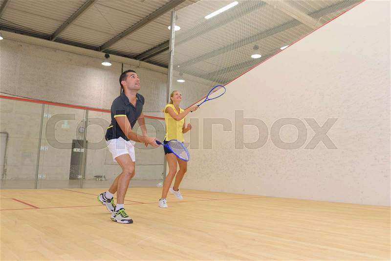 Couple enjoying a game of squash in the squash court, stock photo