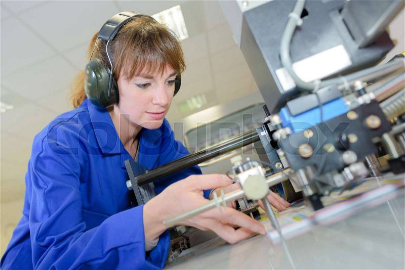 Pretty female student doing practical work at factory, stock photo