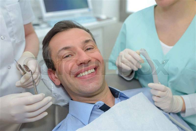 Dentist with assistant diagnostics the oral cavity of male patient, stock photo