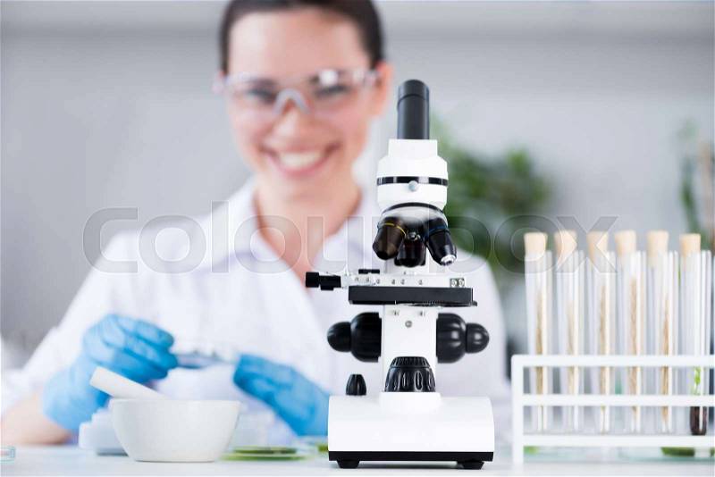 Female scientist during work with microscope at modern biological laboratory, stock photo