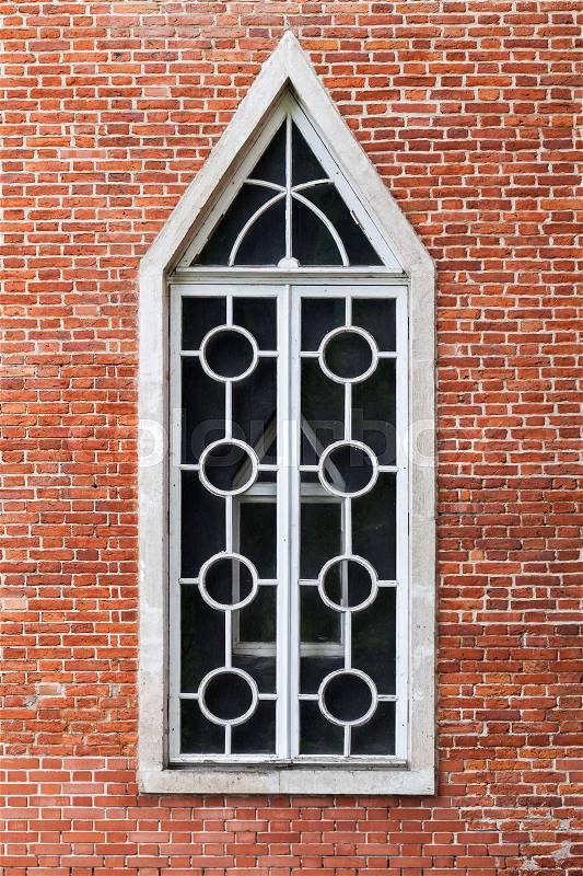 Window in red brick wall, Gothic Revival architecture style. Background texture, stock photo