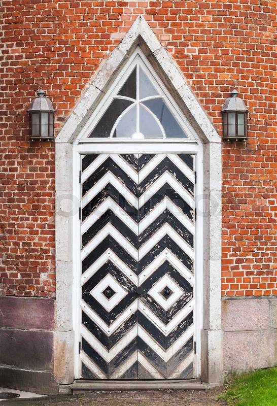 Wooden door in red brick wall, Gothic Revival architecture style. Background texture, stock photo