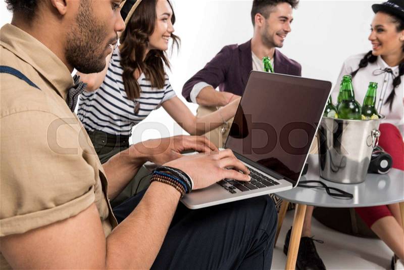 Man using laptop while happy young friends drinking beer isolated on white, stock photo