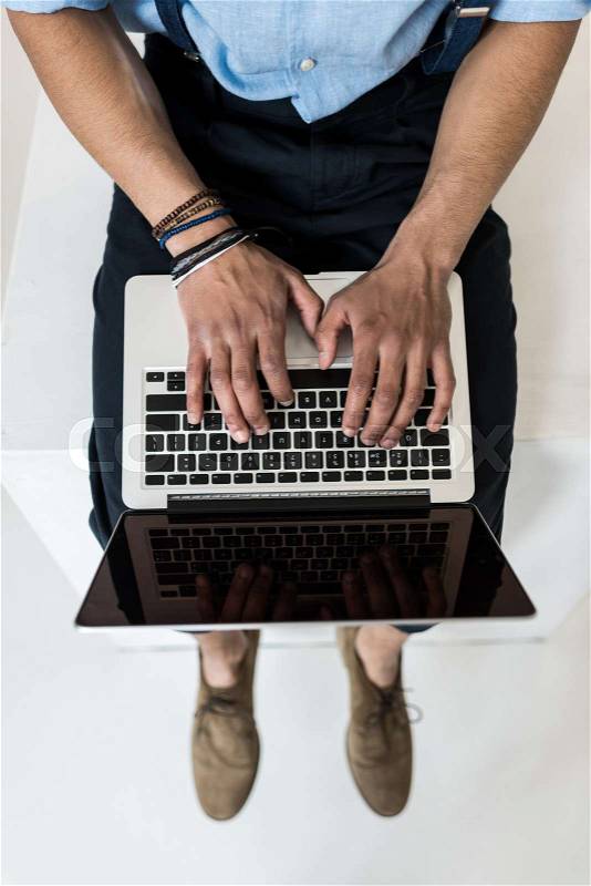 Cropped shot of young man using laptop with blank screen on grey , stock photo