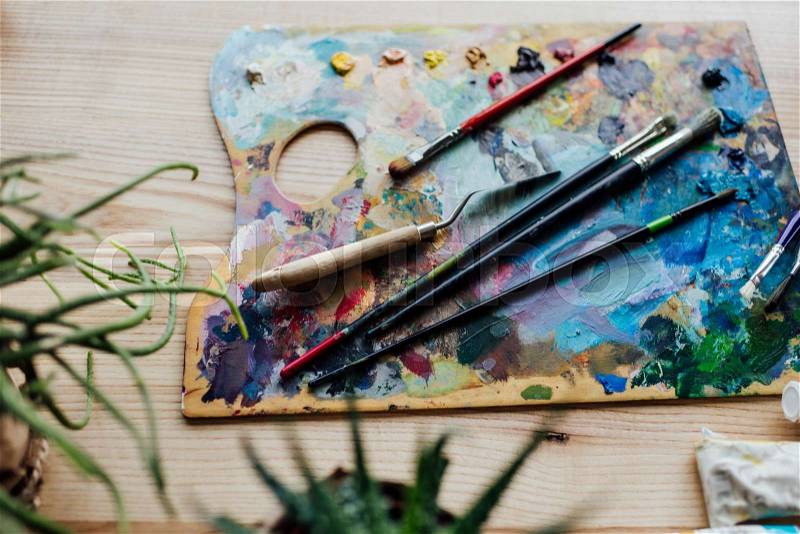 High angle view of artist palette with paint brushes and palette knife on the top, stock photo