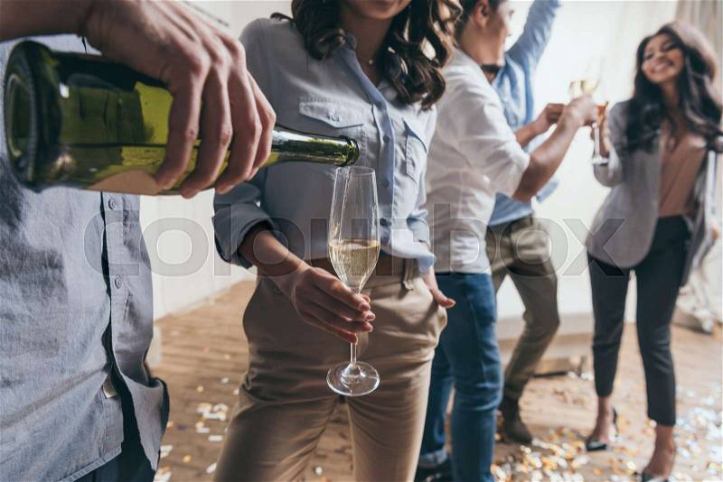 Cropped shot of young man pouring champagne to stylish young woman at party , stock photo