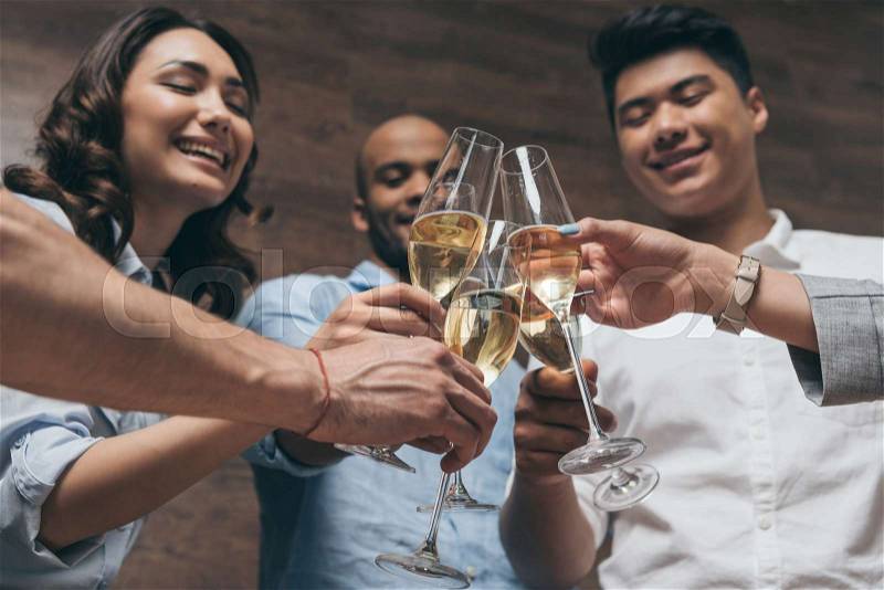 Happy young people clinking glasses of champagne during celebration , stock photo