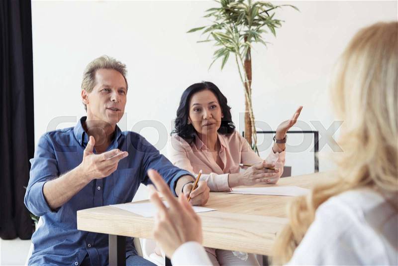 Middle aged colleagues disputing at business meeting in office, stock photo