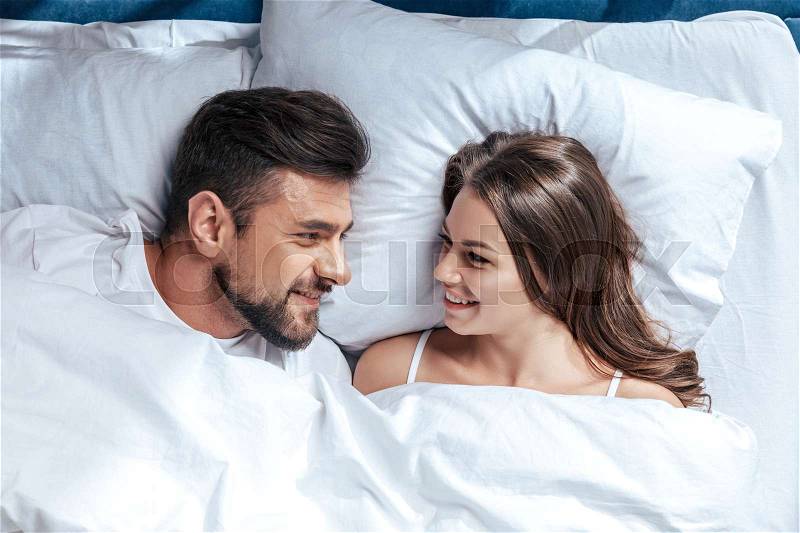 Portrait of young happy loving couple in bed, stock photo