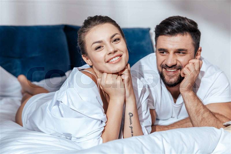 Portrait of young happy loving couple in bed, stock photo