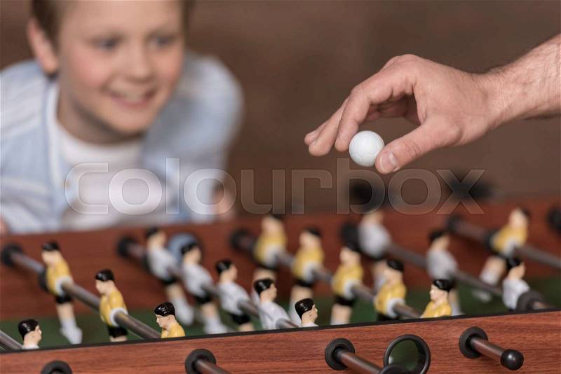 Close-up view boy playing table football and hand with ball in foreground, stock photo