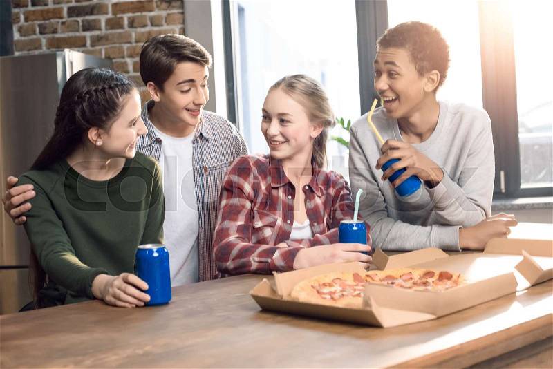 Happy friends spending time together with pizza and soda drinks, eating pizza at home concept, stock photo
