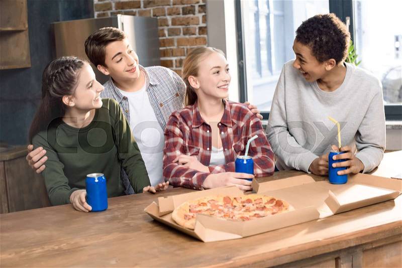 Happy friends spending time together with pizza and soda drinks, eating pizza at home concept, stock photo