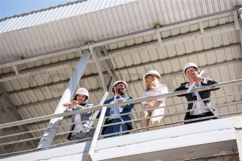 Team of contractors in formal wear talking at construction site, stock photo