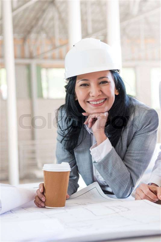 Mature asian contractor in formal wear holding coffee cup and looking at camera, stock photo