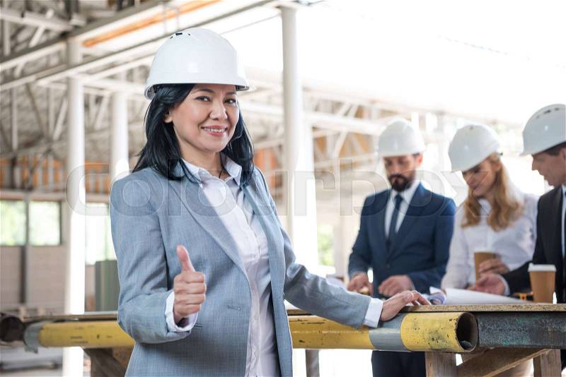 Middle aged asian contractor showing thumb up during meeting at construction site, stock photo
