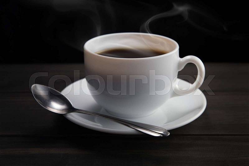 White coffee cup with smoke on black background. Dark background, stock photo