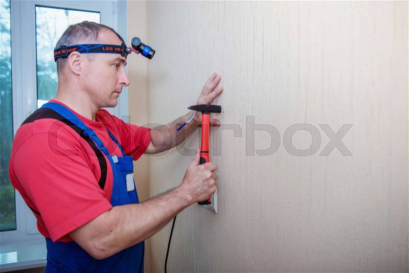 Hammer a nail in wall. Worker with hammer, stock photo