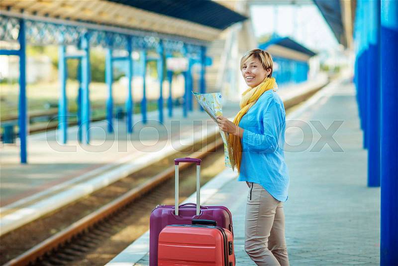Young female waiting for the train at the railway station. female with suitcases, stock photo