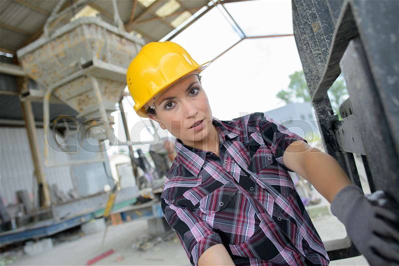 Female engineer monitoring machinery at cement factory, stock photo