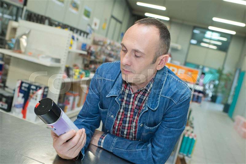 Man in jeans jacket buying spray paint can, stock photo