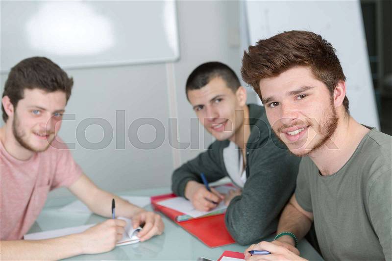 Group of happy students studying together in classroom, stock photo