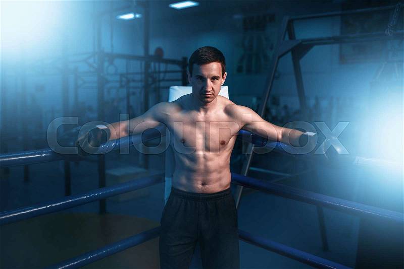 Muscular boxer in black gloves in the corner of the ring. Boxing workout, mens sport, stock photo