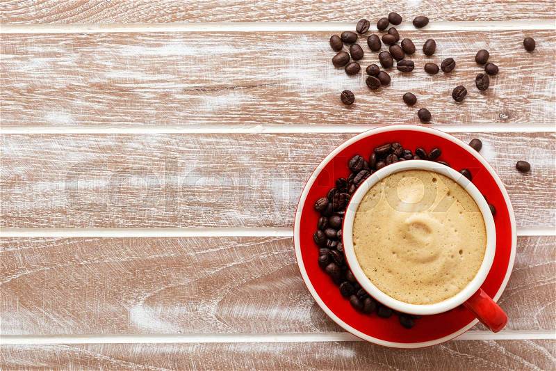 Red cup of coffee with beans on wooden office table background top view, stock photo