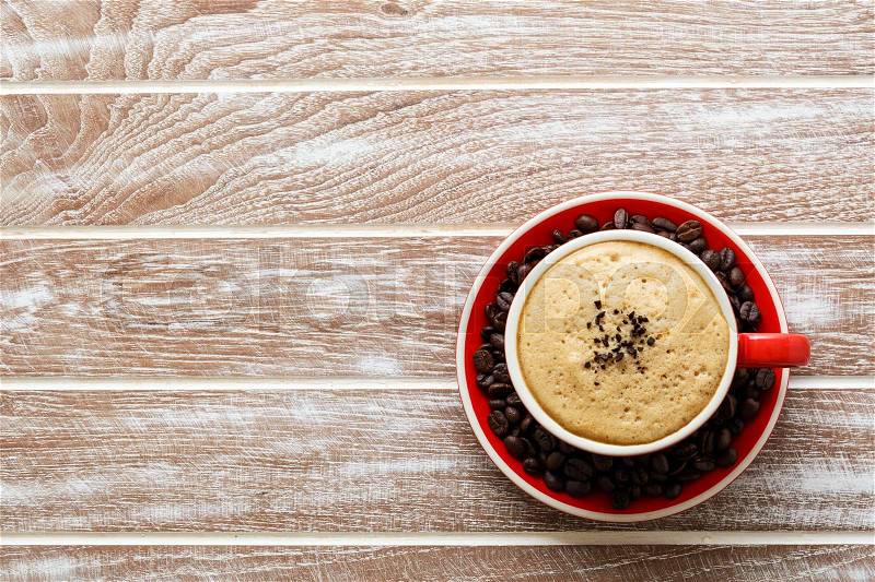 Red cup of coffee with beans on wooden office table background top view, stock photo